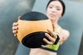 Focus of young woman holding ball while lying on fitness mat Royalty Free Stock Photo