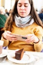 Selective focus of a young woman taking picture of cake in a cafe.