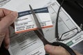 Selective focuse of man cutting fake Medicare cut with fake hospital bill in background. Royalty Free Stock Photo