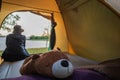 Selective focused on brown teddy bear in tent, Asian woman travel vacation picnic on holiday relax near lake Royalty Free Stock Photo