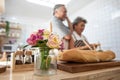 Selective focused on rose on table in kitchen with elder senior asian couple cooking dinner in background.love is all around and