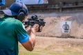 Selective focus of man holding and fire sub machine gun to target in gun shooting competition