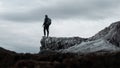 Selective shot of a person wearing backpack standing at the edge of a gray cliff Royalty Free Stock Photo