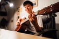Selective, soft focus Asian people playing string music cover a song guitar sitting on chair bedroom in lighting at room