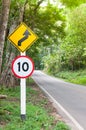 Selective speed limit traffic sign 10 and winding road caution symbol for safety drive in country road in mountain view forest