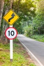 Selective speed limit traffic sign 10 and winding road caution symbol for safety drive in country road in mountain view forest