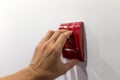 Selectived focus on hand pulling fire alarm on white wall to act Royalty Free Stock Photo