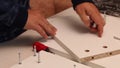 Self-assembly of furniture. A man installs cams in the wooden elements of a tabletop shelf. Close-up