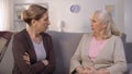 Self-assertive old women arguing and offending each other sitting in living room