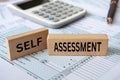 Self assessment text on wooden blocks with tax form and calculator background. Taxation concept Royalty Free Stock Photo