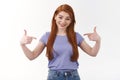 Self-assured smiling caucasian woman with long red hair talking personal achivement, pointing herself at chest and