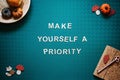 Self-care quotes, make yourself a priority words on green background flat lay. Self-care text wooden letters with autumn