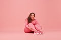 Self-care and well being. Young, laughing, overweight woman training in sportswear against pink studio background