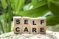 Self care word on wood cubes on green nature background
