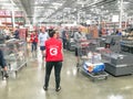 Self-checkout kiosks area with support staff in red uniform at Costco in Churchill Way, Dallas