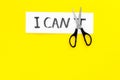 Self confidence concept. Cutting the letter t of written word I can`t by sciccors. Yellow background top view copy space Royalty Free Stock Photo