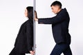 A self-confident business woman is leaning her back against the wall and the man is pushing an impromptu wall. Royalty Free Stock Photo