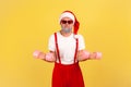 Self confident elderly man in santa claus hat and sunglasses holding dumbbells, pumping muscles before holidays, having fun