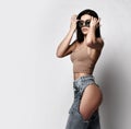 Self-confident sexy adult woman is walking in torn jeans with naked butt, ass, sunglasses and top. Side view Royalty Free Stock Photo