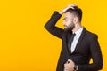 Self-confident young businessman with a beard straightens his hair while standing against a yellow background. Concept