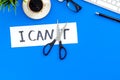 Self-doubt concept. Fight against self-doubt. Sciccors close the letter t of written word I can`t. Office desk. Blue Royalty Free Stock Photo