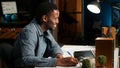 Self employed Black man multitasking at home taking handwritten notes Royalty Free Stock Photo