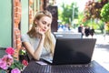 Self employed freelancer Caucasian woman working with her phone and laptop in a restaurant terrace in the street in a sunny day Royalty Free Stock Photo