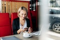 A self-employed woman is working with her phone and laptop on the terrace of a restaurant Royalty Free Stock Photo