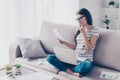 Self-employed young concentrated woman in glasses looking at doc