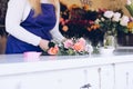 Self-employed young woman owner of florist shop arranging bouquet of roses Royalty Free Stock Photo