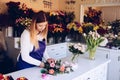 Self-employed young woman owner of florist shop arranging bouquet of roses Royalty Free Stock Photo