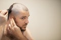 Self haircut, a man cuts his head with a clipper at home in front of a mirror Royalty Free Stock Photo