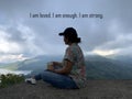 Self healing with affirmation words - I am loved. I am enough. I am strong. With an adventure woman sitting alone holding a cup of