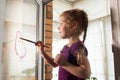 Self-isolation at home. Child quarantined girl paints a rainbow on a glass window. Art Therapy Royalty Free Stock Photo