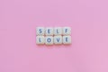 Self love message made with board game letters, over a soft pink background Royalty Free Stock Photo