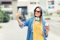 Self portrait of happy beautiful modern fashionable young woman drinking coffee on city street Royalty Free Stock Photo