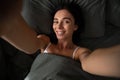 Self portrait of woman lying in bed shooting selfie on front camera enjoying recreation biting finger having online meeting with