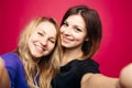 Two positivity girls taking self portrait smiling, posing at pink background. Royalty Free Stock Photo