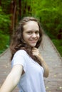 Self portrait of young smiling smiling woman on nature in forest or summer park. Travel. Selfie