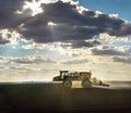 Big self-propelled sprayer in the field cultivates arable land against the fantastic light from under the clouds