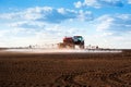 Big red self-propelled red sprayer with long arms disperses fertilizers on agricultural fields, rear view with beautiful clouds Royalty Free Stock Photo