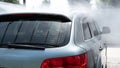 Self-service car wash. Washing a car in a carwash using a high-pressure sprayer. Gray car. Saving concept Royalty Free Stock Photo