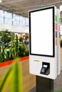 Self-service electronic counter with blank mockups on white screen and payment terminal in fast food restaurant, shopping mall.