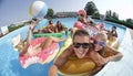 SELFIE: Cheerful smiling friends making selfie on fun colorful floaties in pool