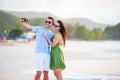 Selfie couple taking pictures on the beach. Tourists people taking travel photos on summer holidays. Royalty Free Stock Photo