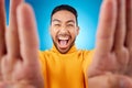 Selfie, excited and portrait of a man in studio with hands and shout emoji. Face of asian male or fashion model on blue