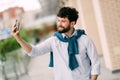 Selfie. Excited young man is making selfie on a camera on a walk in spring town outdoors