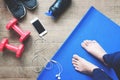 Selfie of feet yoga woman, smartphone, sport equipments and sport shoes on wood