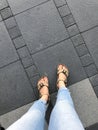 Selfie of female feet in sandals and jeans on the pavement. Royalty Free Stock Photo