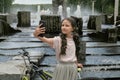 Selfie of a girl near a Bicycle and a fountain. Long hair. Outdoor activity.